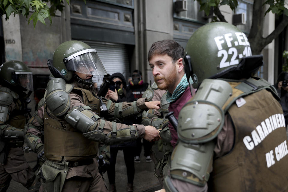 Riot police detain an anti-government demonstrators in front of La Moneda presidential palace in Santiago, Chile, Friday, Nov. 1, 2019. Groups of Chileans continued to protests as government and opposition leaders debated the response to nearly two weeks of protests that have paralyzed much of the capital and forced the cancellation of two major international summits. (AP Photo/Rodrigo Abd)