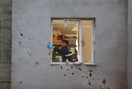 Police forensic experts examine a building which was damaged after a rocket fired from Syria landed nearby, in the border town of Kilis, Turkey January 22, 2018. REUTERS/Osman Orsal