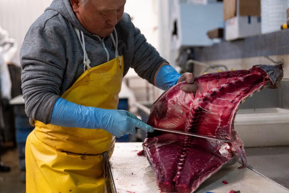 A man cuts an ahi, or yellow-fin tuna, at the Fulton Fish Market in New York City.