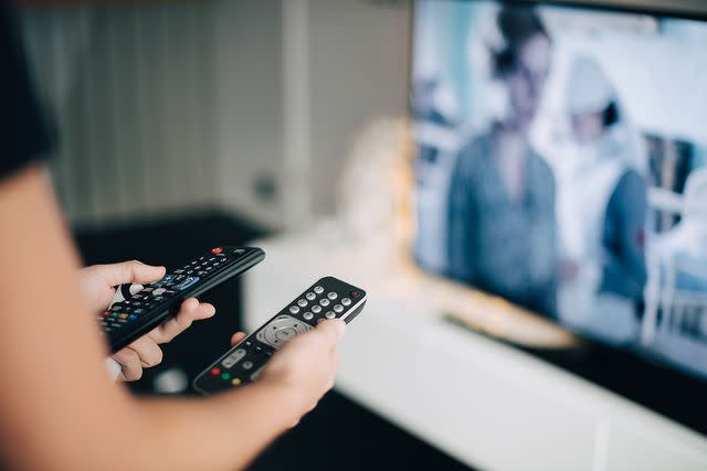 <p>Getty</p> Stock image of person holding two remote controls.