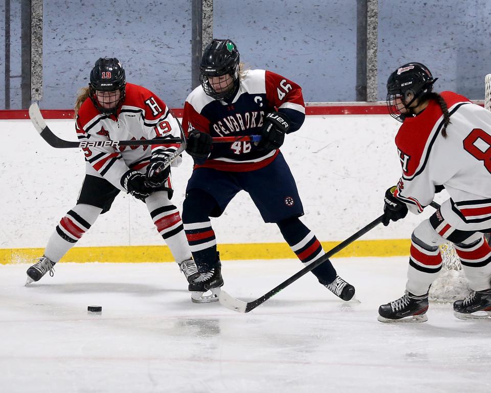 Hingham’s Catherine Flynn lifts the stick of Pembroke's Jennifer Birolini while Hingham’s Reese Pompeo goes in to collect the puck during second period action of their game against Pembroke at Pilgrim Arena on Saturday, Feb. 18, 2023.