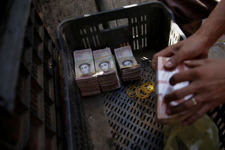 Stacks of 100 bolivar notes are seen in a plastic crate at a stall in a street market near Venezuela's Central Bank in Caracas, Venezuela December 16, 2016. REUTERS/Marco Bello
