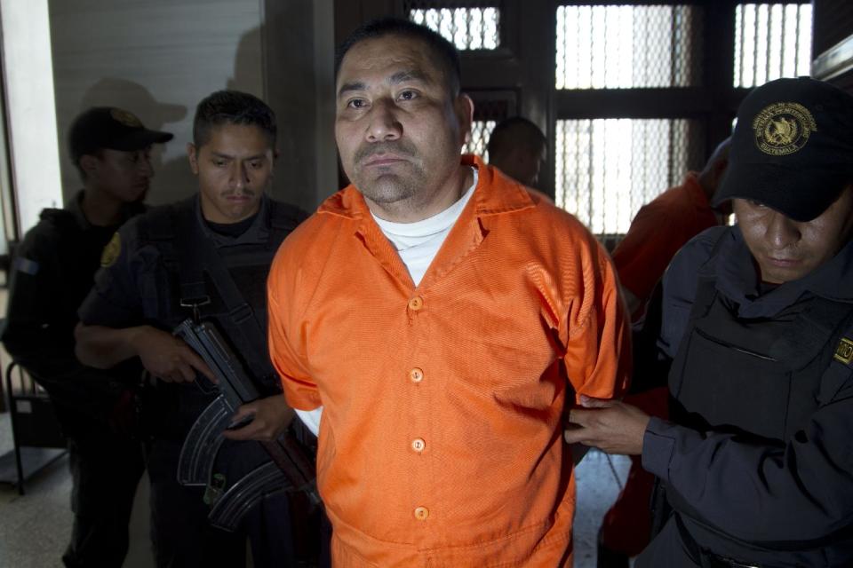 Police agents escort Guatemalan Hugo Alvaro Gomez to a courtroom in Guatemala City, Friday, Feb. 21, 2014. Gomez and eight other alleged members of Los Zetas drug cartel were each sentenced to 106 years in prison, after they were found guilty of participating in the May 14, 2011 massacre of 27 farm laborers in Peten, north of Guatemala City. (AP Photo/Moises Castillo)