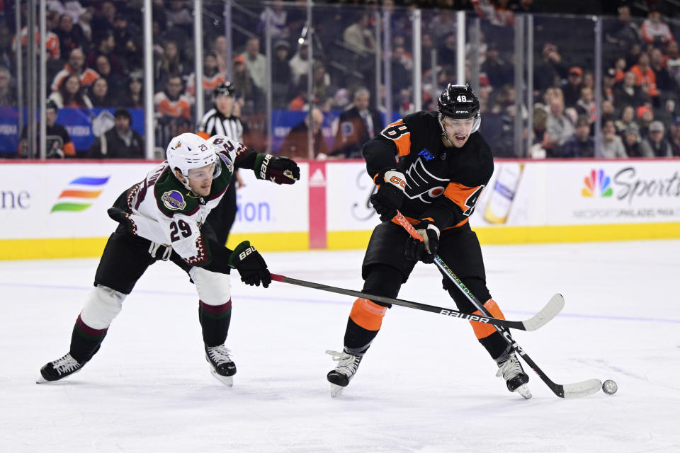 Philadelphia Flyers' Morgan Frost, right, passes the puck against the defense of Arizona Coyotes' Barrett Hayton during the second period of an NHL hockey game, Monday, Feb. 12, 2024, in Philadelphia. (AP Photo/Derik Hamilton)