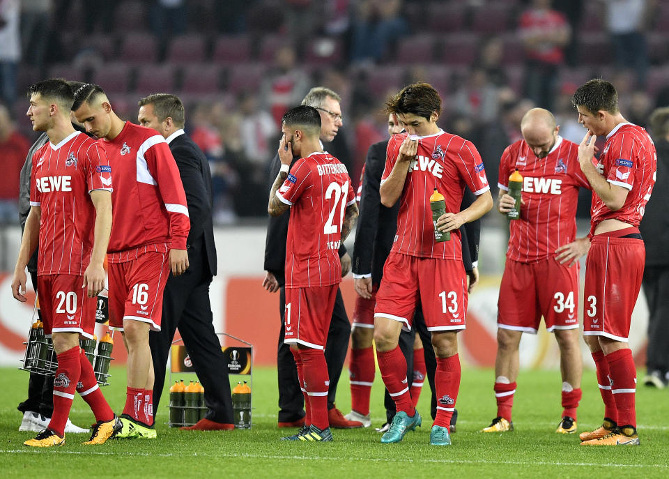 Cologne’s head coach Peter Stoeger, center, and members of the team stay on the pitch after the Europa League group H soccer match