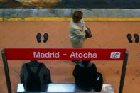 Commuters wearing protective face masks wait on a platform at Atocha train station in Madrid