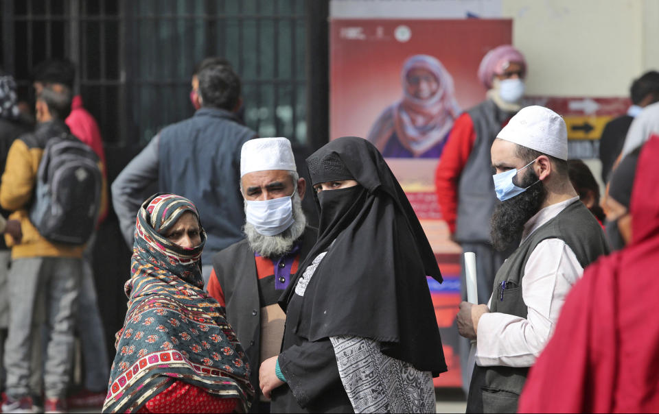 People wearing face masks as a precaution against the coronavirus wait outside a government hospital in Jammu, India, Tuesday, Feb. 16, 2021.(AP Photo/Channi Anand)