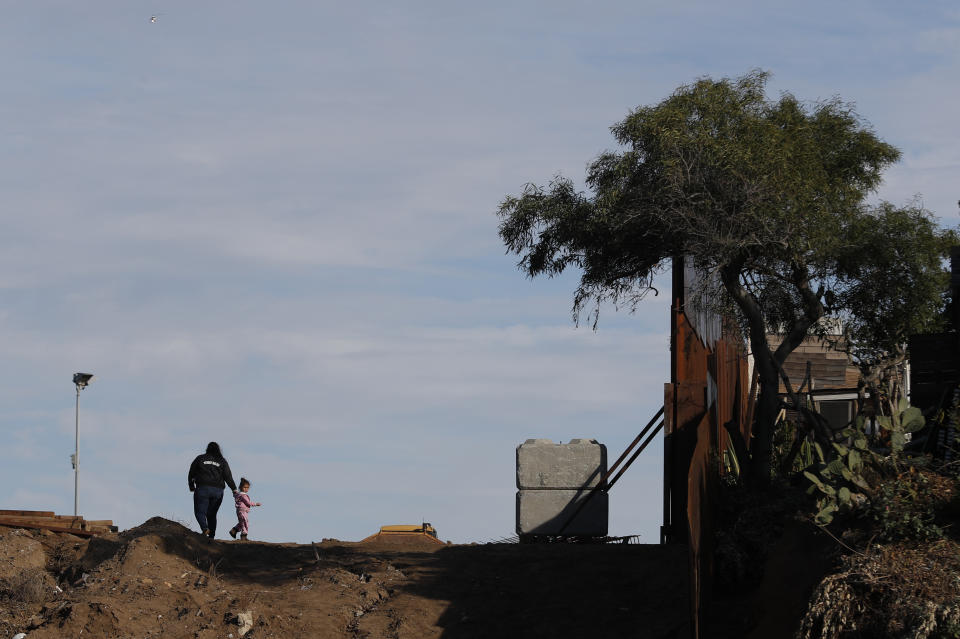 Three-year-old Honduran migrant Charlot Andrea looks back toward her grandparents standing in Tijuana, Mexico, as she and her mother cross into San Ysidro, California, on Tuesday, Dec. 4, 2018. Rachel Rivera, 19, and her daughter Charlot crossed under the U.S. border wall through a hole. Rivera planned to surrender to the U.S. border patrol and request asylum. (AP Photo/Rebecca Blackwell)