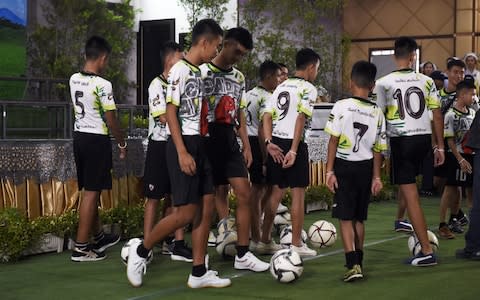 Some of the twelves boys play football before the press conference - Credit: AFP