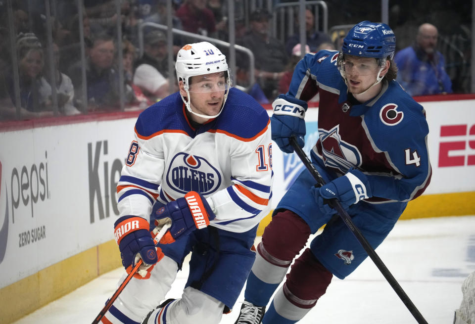 Edmonton Oilers left wing Zach Hyman, left, wraps around the net as Colorado Avalanche defenseman Bowen Byram covers during the second period of an NHL hockey game Tuesday, April 11, 2023, in Denver. (AP Photo/David Zalubowski