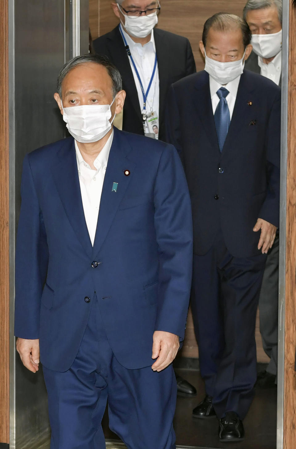 Japan’s Prime Minister and head of ruling Liberal Democratic Party Yoshihide Suga, left, and the party's secretary general Toshihiro Nikai, second right, arrive for a meeting in Tokyo Friday, Sept. 2021. Suga won’t run for governing party leadership election, indicating he will step down as Japanese leader later at the end of this month, NHK said. (Kyodo News via AP)