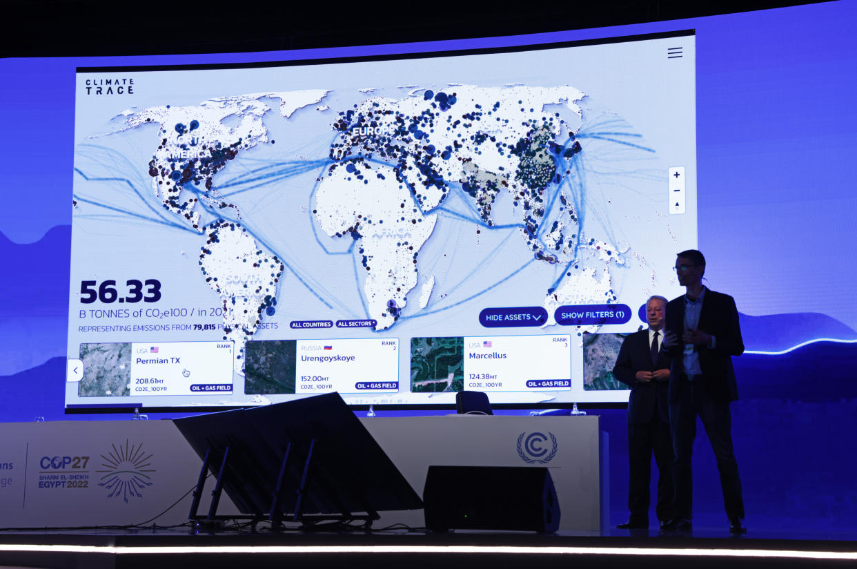 Vice President Al Gore and Gavin McCormick in front of a detailed map of the globe showing the lines of communication and centers of population covered by the new Climate TRACE platform,.