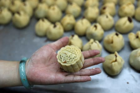 An employee poses with an anti-extradition mooncake with Chinese words "Support each other" at Wah Yee Tang Bakery in Hong Kong