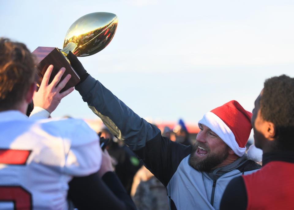 Whitharral football coach Jeremy Holt hands the team its trophy after a win over Balmorhea in the Region I-1A Division II final Saturday, Nov. 26, 2022, at Spieker Stadium in Hermleigh.