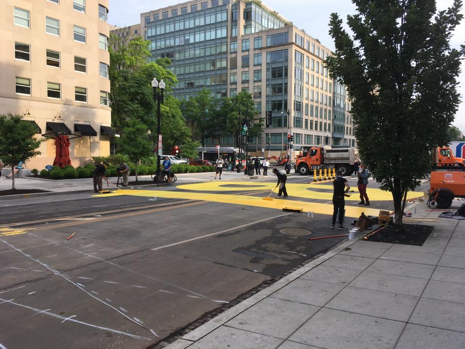 City dump trucks block off the street as people paint "BLACK LIVES MATTER" on 16th Street near the White House in Washington, D.C.