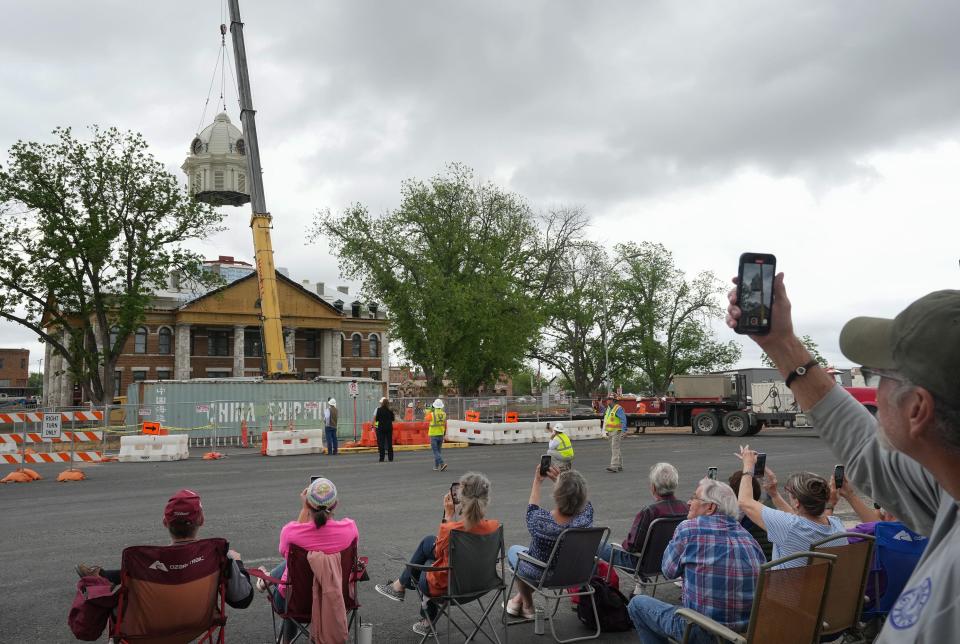 People watch a new crown get hoisted by a crane to the top of the Mason County Courthouse on April 19. Some of the people watching the restoration recalled coming to the square the night the courthouse burned in 2021.