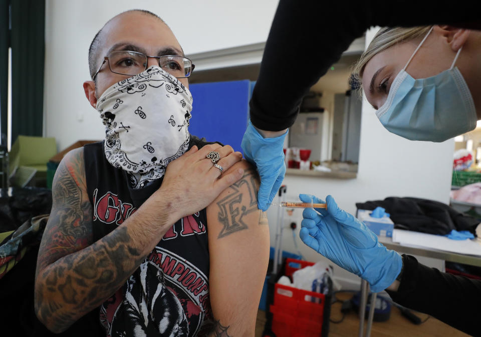 Apprentice Nursing's Associate Ellie Bull administers the Astra Zeneca vaccine to a homeless person at the Wellcome Centre in Ilford, east London, Friday, Feb. 5, 2021. The British health service NHS England have started to vaccinate homeless vulnerable people. (AP Photo/Frank Augstein)