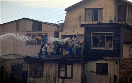 Residents throw water on a fire (not pictured) at the location where a forest fire burned several neighbourhoods in the hills in Valparaiso city, northwest of Santiago, April 13, 2014. REUTERS/Cristobal Saavedra