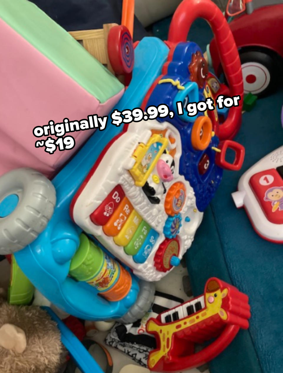 Various children's toys, including a walker with interactive buttons and a toy giraffe piano, are scattered on the floor