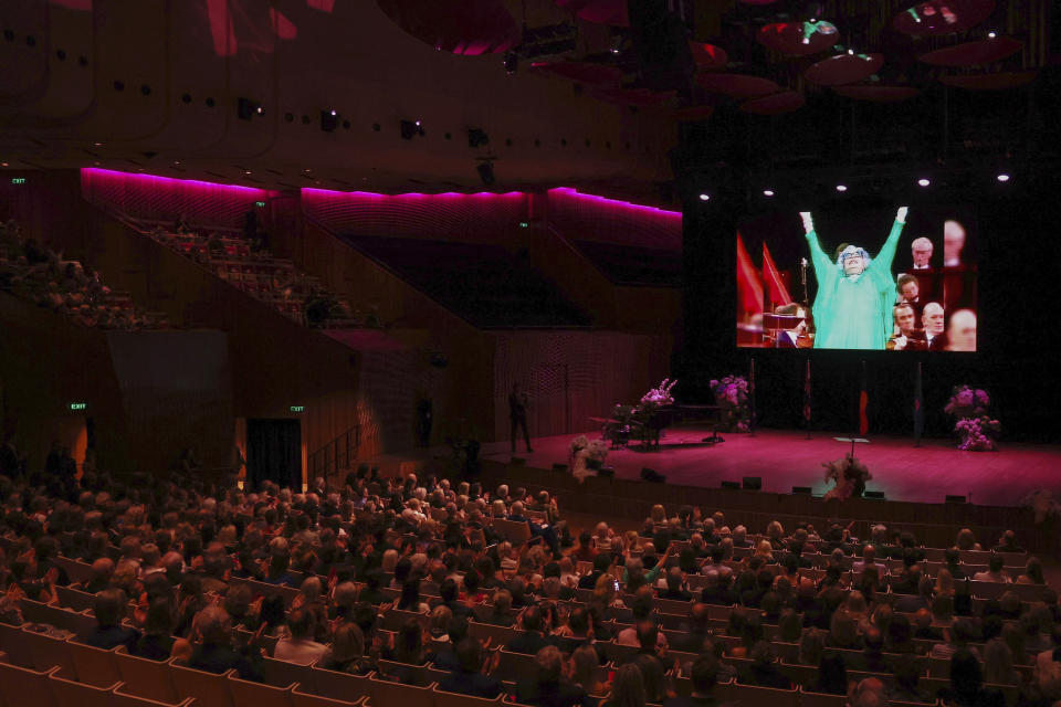 An historical performance by Barry Humphries as the character Dame Edna Everage is shown on a screen during the State Memorial Service for Australian comedian and actor Barry Humphries at the Sydney Opera House in Sydney, Friday, Dec. 15, 2023. King Charles III has paid tribute to the late Barry Humphries at a state memorial service with a message that recalled the monarch's own apprehension when the comedian's alter ego Dame Edna Everage played a prank on him in a royal box a decade ago (David Gray/Pool Photo via AP)