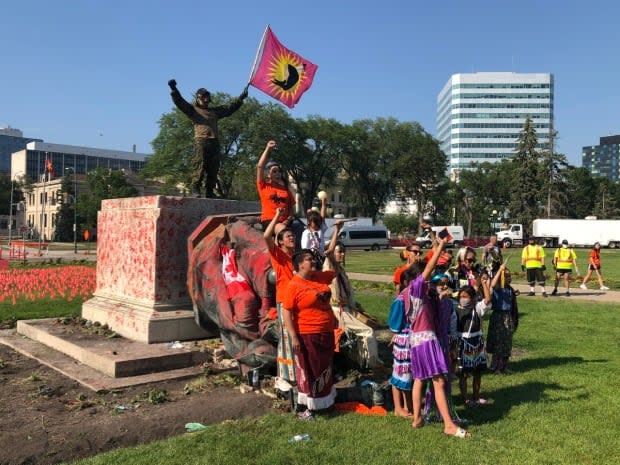 People celebrate after a statue of Queen Victoria was toppled on Thursday at the Manitoba Legislature.  (Travis Golby/CBC - image credit)