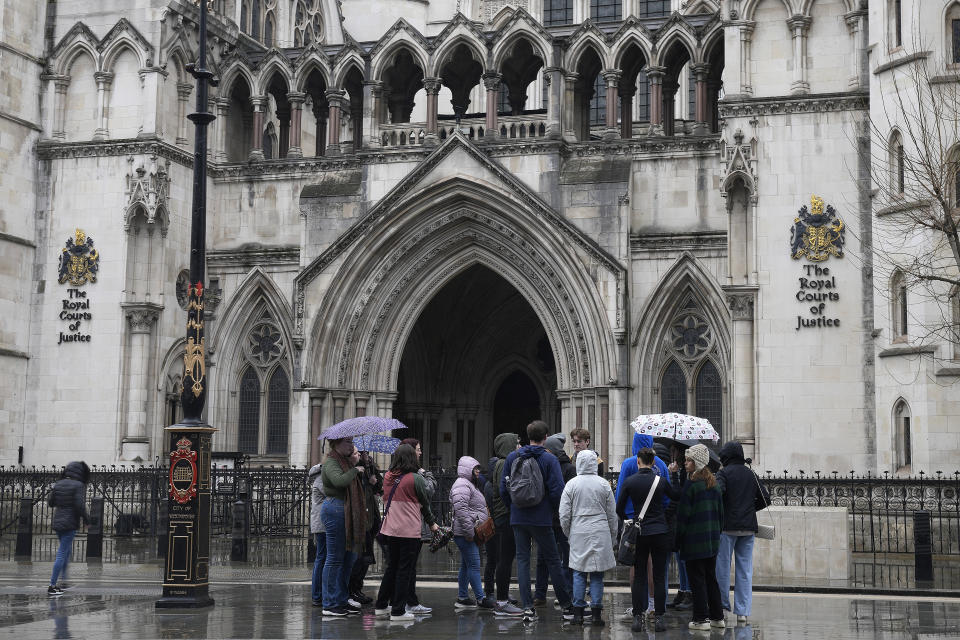 Personas de pie frente a la Corte Real de Justicia en Londres, el 17 de marzo de 2023. El príncipe Enrique, duque de Sussex, demandó a la editorial Associated Newspapers Ltd. del diario Mail on Sunday por un artículo que alega que trató de silenciar otro pleito legal ante la negativa del gobierno británico para permitirle pagar por seguridad policial. (Foto AP/Frank Augstein)