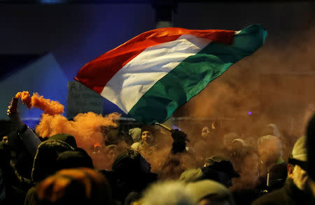 Hungarian national flag and smoke from flares are pictured during a protest against a proposed new labor law, billed as the "slave law", outside the headquarters of the Hungarian state television in Budapest, Hungary, December 17, 2018. REUTERS/Bernadett Szabo