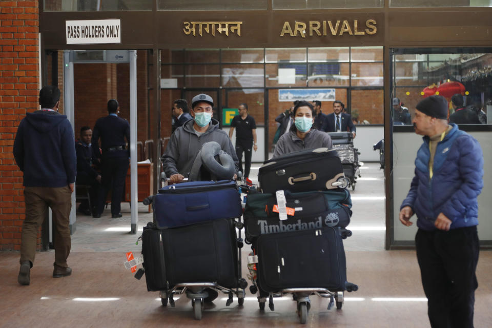 Passengers wearing face masks arrive at Tribhuwan International airport in Kathmandu, Nepal, Tuesday, Jan. 28, 2020. Authorities have started screening passengers after one confirmed case of a new coronavirus infection was detected in the Himalayan country. (AP Photo/Niranjan Shrestha)