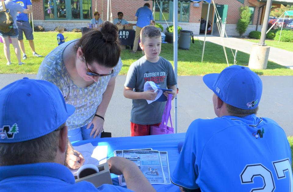 Finnigan Newburn, 8, of Battle Creek talks to some Battle Jacks players as he gets his free hat and signs up for the Willard Library Summer Reading Program at an event at the Helen Warner Branch on Tuesday.