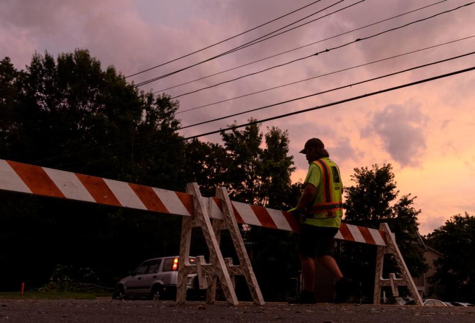 A person blocks Cole Mill Road due to a downed tree following strong storms in Durham, N.C. on Tuesday, Aug. 15, 2023.