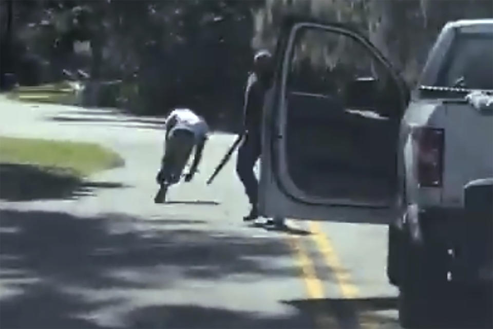 This image from video posted on Twitter Tuesday, May 5, 2020, purports to show Ahmaud Arbery stumbling and falling to the ground after being shot as Travis McMichael stands by holding a shotgun in a neighborhood outside Brunswick, Ga., on Feb. 23, 2020. The AP has not been able to verify the source of the video. Father and son Greg and Travis McMichael and their neighbor, William “Roddie” Bryan, face an automatic life sentence if they're convicted of murder in Glynn County Superior Court. The three white men in pickup trucks pursed Arbery, a 25-year-old Black man, after spotting him running in their neighborhood last year (Twitter via AP)