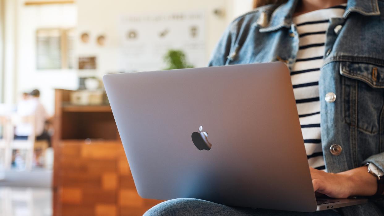  A woman sitting down with a MacBook laptop her lap. 