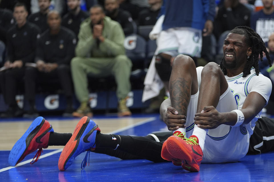 Minnesota Timberwolves center Naz Reid, front, sits on the floor after sustaining an injury during the first half of the team's NBA basketball game against the Brooklyn Nets, Saturday, Feb. 24, 2024, in Minneapolis. (AP Photo/Abbie Parr)