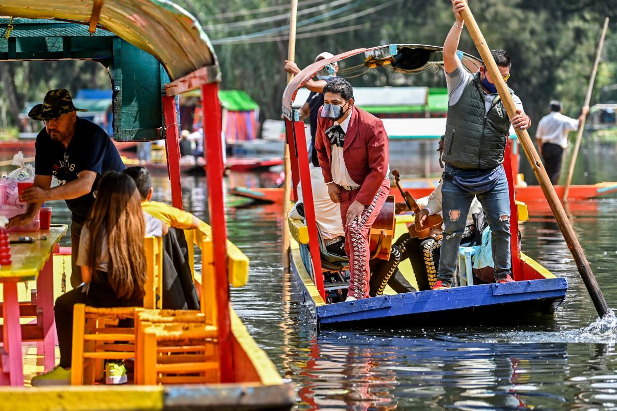 A Mariachis wearing a face mask and shield to follow sanitary protocols against the COVID-19 offers customers to play a song on a "trajinera" at the Nativitas canal pier in Xochimilco, a network of canals and floating gardens that is one of Mexico City's top tourist attractions, after its reopening, on August 23, 2020, amid the new coronavirus pandemic. (Photo by PEDRO PARDO / AFP) (Photo by PEDRO PARDO/AFP via Getty Images)