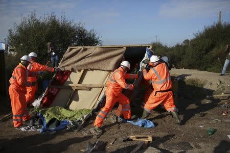 Workmen remove debris as they tear down makeshift shelters on the second day of the evacuation of migrants and their transfer to reception centers in France, as part of the dismantlement of the camp called the "Jungle" in Calais, France, October 25, 2016. REUTERS/Neil Hall