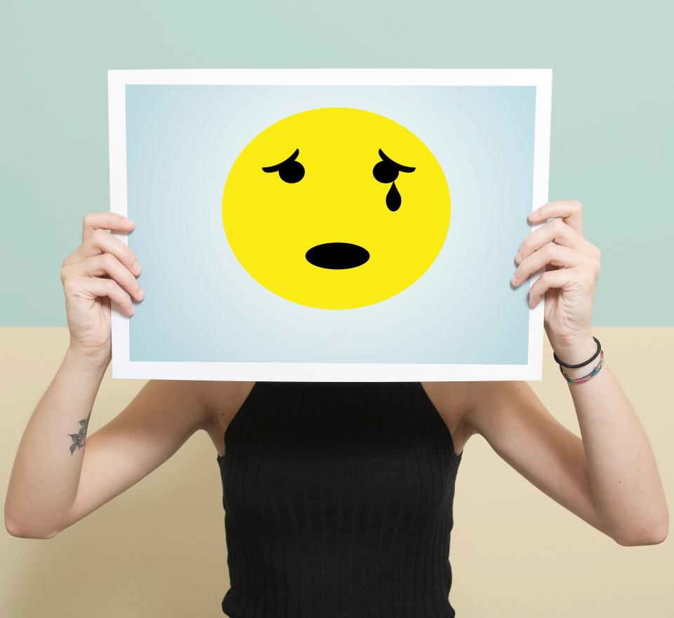 Photo of a woman holding a poster with a sad, crying face on it