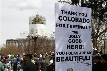 A man holds a sign referring to Colorado legalizing marijuana with the state capitol dome in the background at the 4/20 marijuana holiday in Civic Center Park in downtown Denver April 20, 2013. REUTERS/Rick Wilking