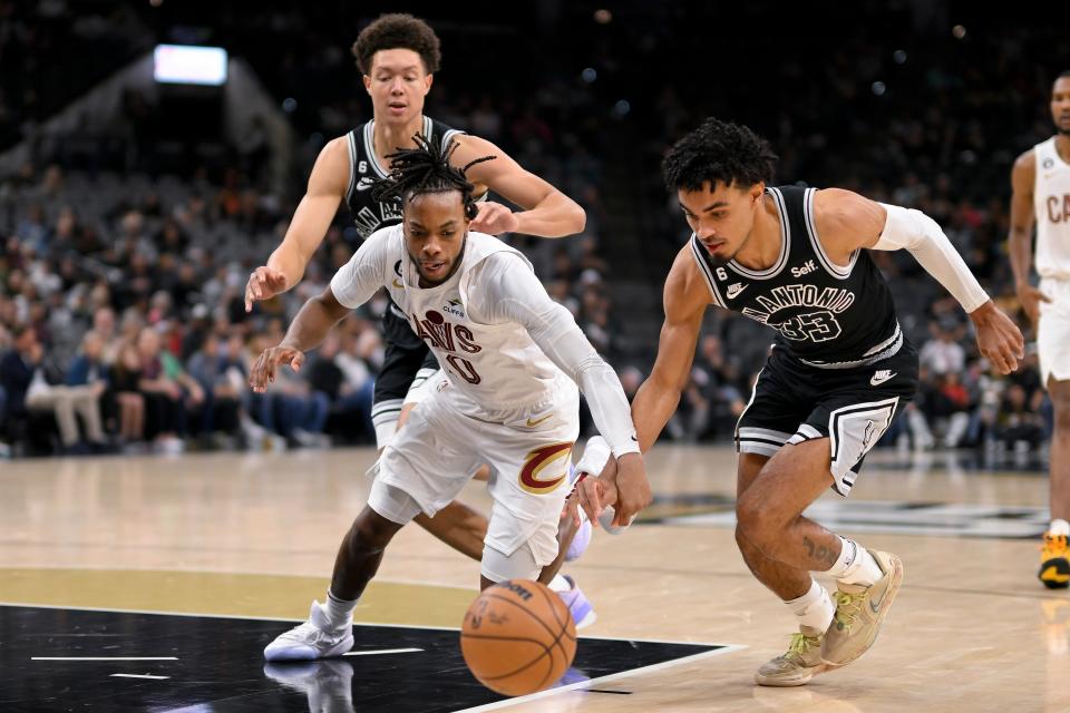 Cleveland Cavaliers' Darius Garland, front left, and San Antonio Spurs' Tre Jones (33) chase the ball as Spurs' Isaiah Roby, back left, watches during the first half of an NBA basketball game, Monday, Dec. 12, 2022, in San Antonio. (AP Photo/Darren Abate)