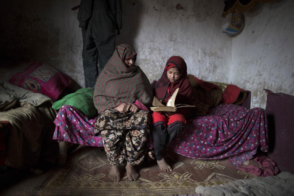 Tadjroshan poses for a photograph with her daughter Ayman at their house in a slum on the outskirts of Islamabad