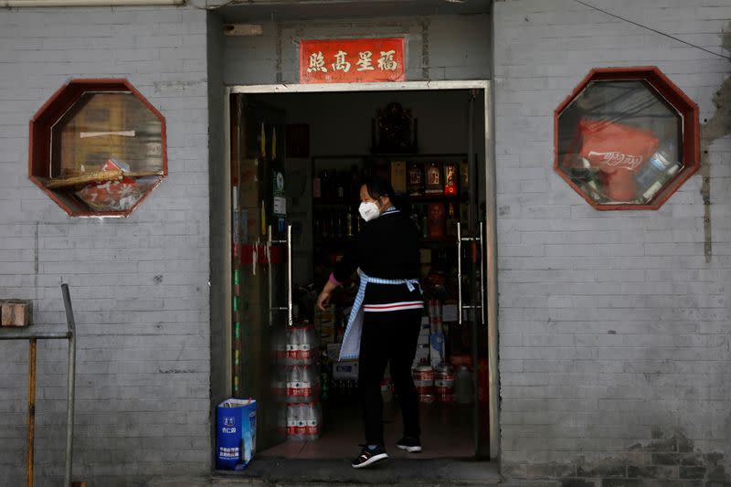 Woman wearing a face mask stands at an entrance to a store in Beijing