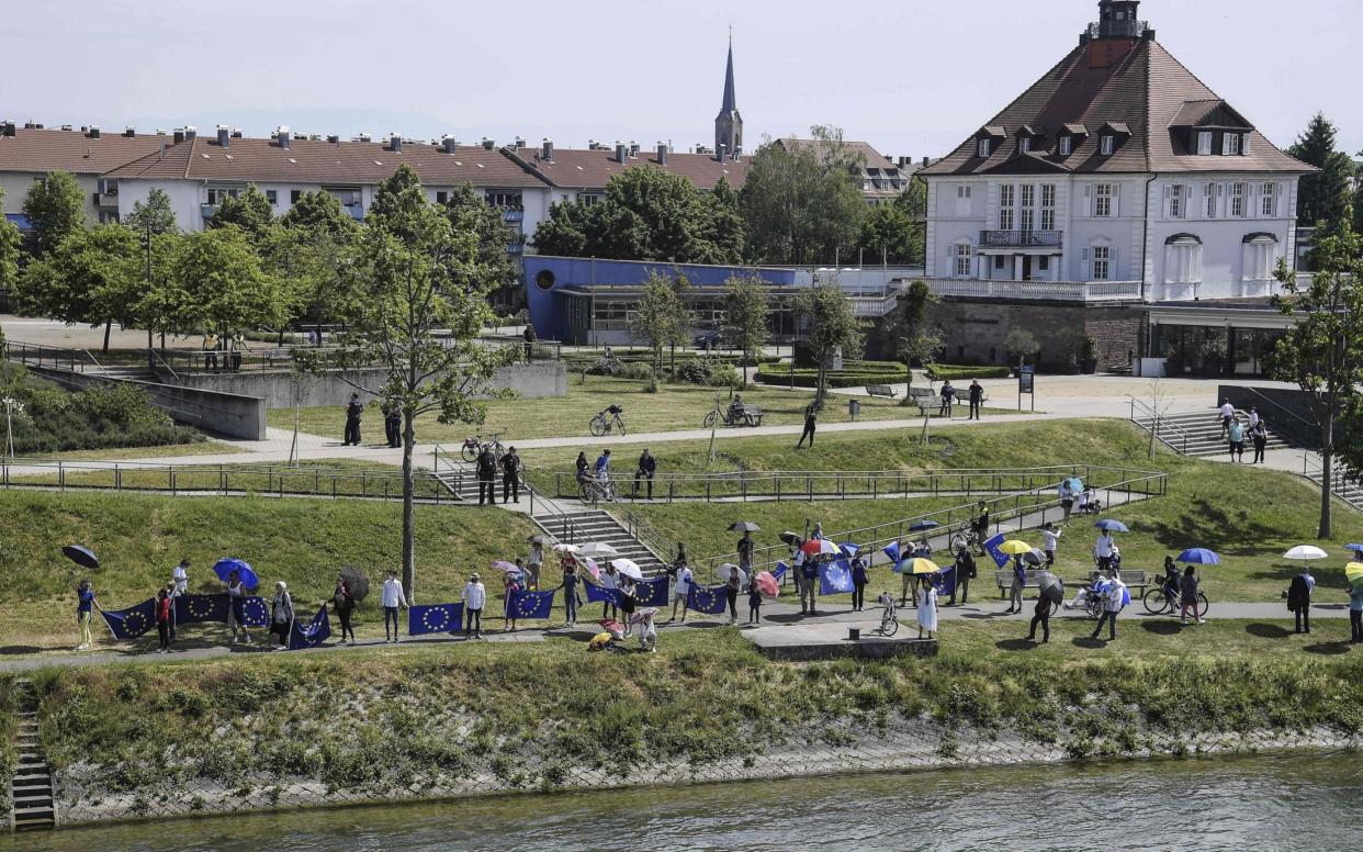 This picture taken on May 9, 2020 from the French side of the Europe Bridge in Strasbourg shows few dozens of Pro-European Union activists waving EU flags on the German side of the Rhine river as they mark Europe Day and protest against the closing of the borders between France and Germany as a results of the two countries' measures to stop the spread of the COVID-19 pandemic caused by the novel coronavirus. (Photo by FREDERICK FLORIN / AFP) (Photo by FREDERICK FLORIN/AFP via Getty Images) - FREDERICK FLORIN/AFP