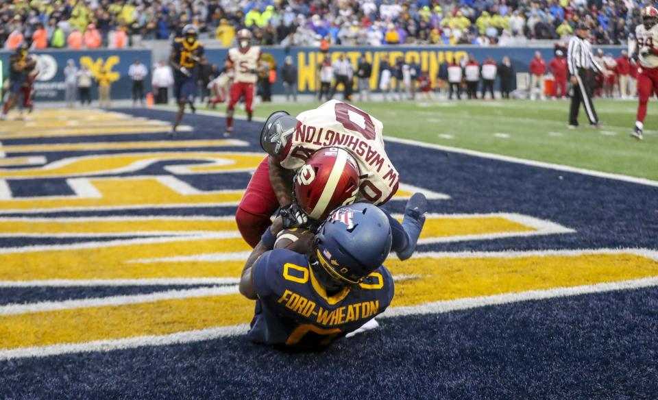 Nov 12, 2022; Morgantown, West Virginia, USA; West Virginia Mountaineers wide receiver Bryce Ford-Wheaton (0) catches a pass for a touchdown over Oklahoma Sooners defensive back Woodi Washington (0) during the third quarter at Mountaineer Field at Milan Puskar Stadium. Mandatory Credit: Ben Queen-USA TODAY Sports