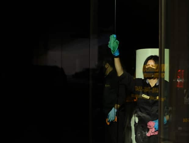 A women cleans the store front window while wearing her protective mask in Toronto on December 17, 2020. (Nathan Denette/The Canadian Press - image credit)