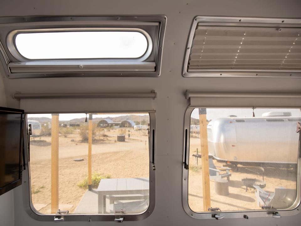 Autocamp Joshua Tree's Airsteram trailer with windows showing the outside desert and nearby traielr.