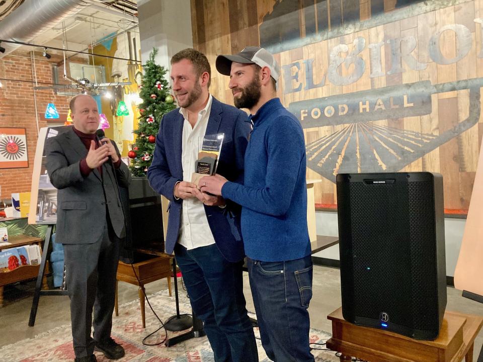 Colorado Governor Jared Polis (left) presents Zach Cytryn and Nathan Stern (right), the lead developers of Fuel & Iron Food Hall, with an award for historic preservation on Dec. 12, 2023.