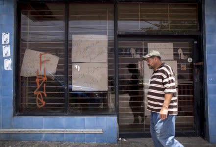 FILE PHOTO: A man walks past a closed store with signs reading