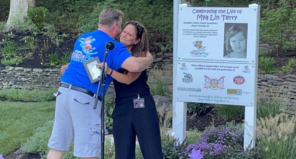 Bill Lavin, left, founder of Where Angels Play Foundation, hugs Ocean Township Councilwoman Kelly Terry at the dedication of a new playground featuring a photo of her late daughter, Mya Lin Terry.