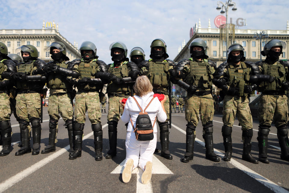 A woman kneels in front of a riot police line as they block Belarusian opposition supporters rally in the center of Minsk, Belarus, Sunday, Aug. 30, 2020. Opposition supporters whose protests have convulsed the country for two weeks aim to hold a march in the capital of Belarus. (AP Photo)