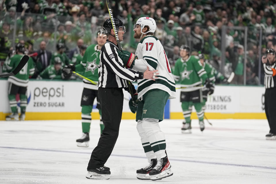 Linesman David Brisebois (96) escorts Minnesota Wild's Marcus Foligno (17) off the ice after Foligno was issued a game misconduct in the first period of Game 5 of the team's NHL hockey Stanley Cup first-round playoff series against the Dallas Stars, Tuesday, April 25, 2023, in Dallas. (AP Photo/Tony Gutierrez)