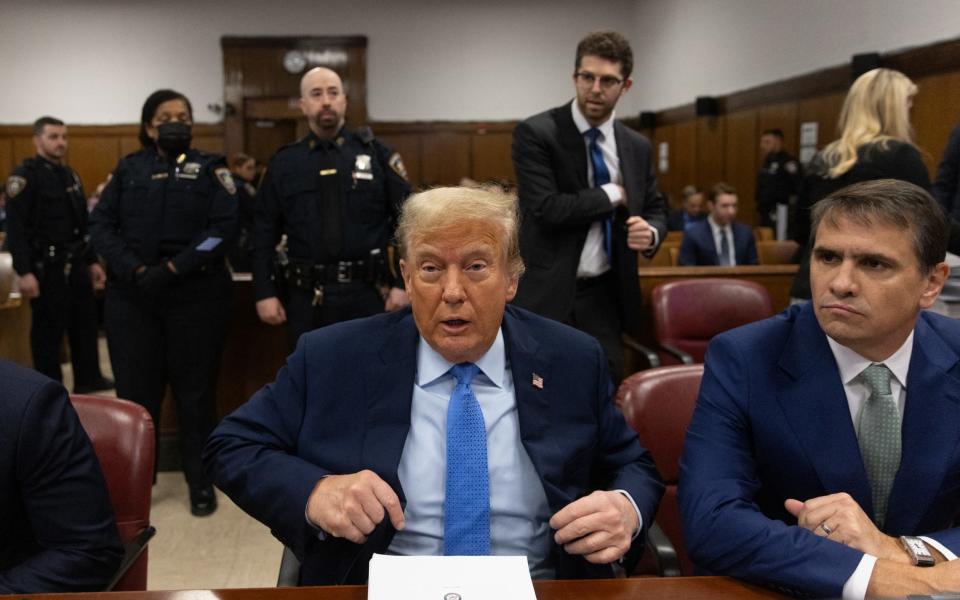 Donald Trump, sitting with attorney Todd Blanche (R),